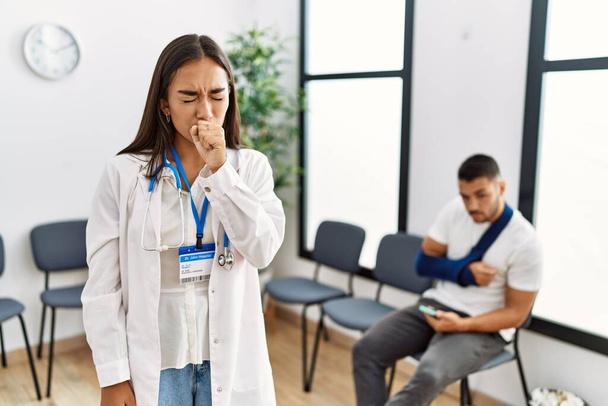 Fiatal ázsiai orvos nő a váróteremben egy törött karú férfival rosszul érzi magát és köhög, mint a hideg vagy hörghurut tünete. az egészségügyi ellátás fogalma.  - Fotó, kép