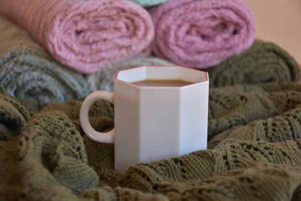 White cup of coffee served on multicolor knitted blankets background - Φωτογραφία, εικόνα