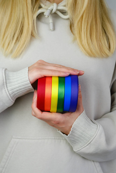 Rainbow LGBT flag from ribbon in the hands of a woman. LGBTQIA Pride Month in June. Lesbian Gay Bisexual Transgender. Gender equality. Human rights and tolerance. Rainbow flag. Love concept - Фото, изображение