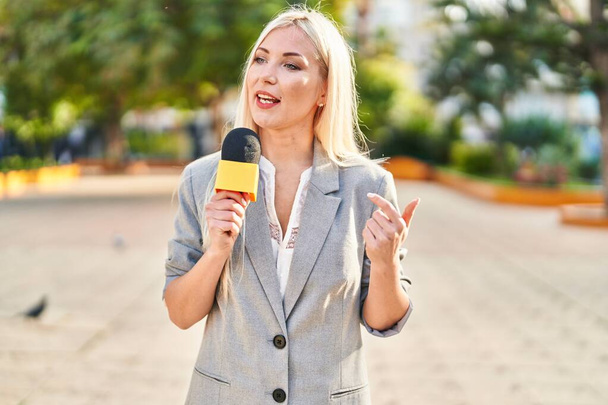 Nuori blondi nainen toimittaja työskentelee mikrofonin avulla puistossa - Valokuva, kuva