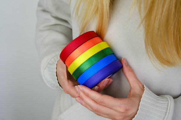 Rainbow LGBT flag from ribbon in the hands of a woman. LGBTQIA Pride Month in June. Lesbian Gay Bisexual Transgender. Gender equality. Human rights and tolerance. Rainbow flag. Love concept - Foto, Bild