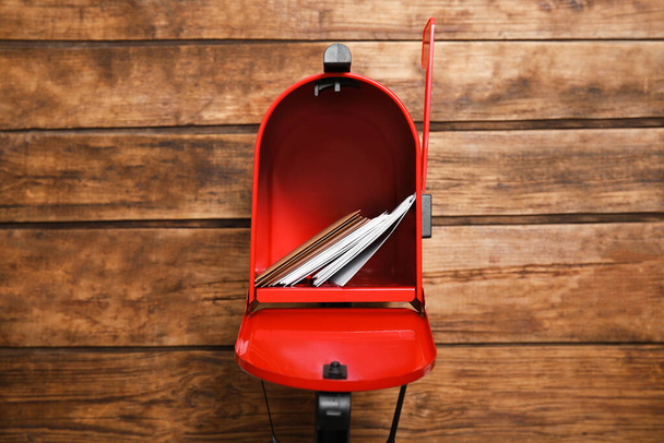 Open red letter box with envelopes against wooden background - 写真・画像