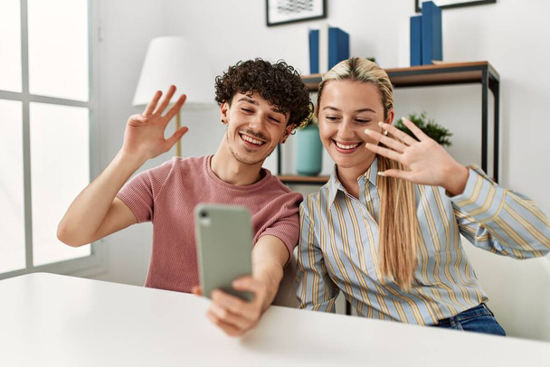 Nuori pari hymyilevä onnellinen videopuhelu älypuhelimella kotona. - Valokuva, kuva