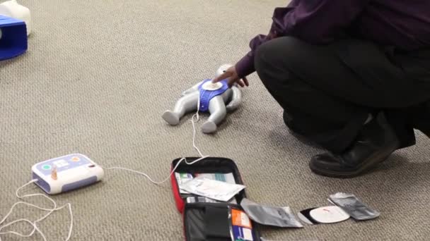 Staff is training to conduct first aid CPR with a dummy doll and AED machine - Materiaali, video