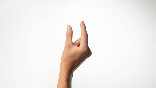 Женские пальцы показывают небольшое расстояние на белом фоне. Высокое качество фото - Фото, изображение