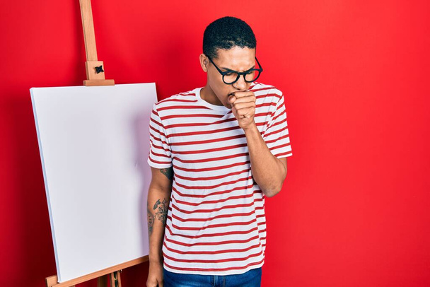 Jeune homme afro-américain debout près du chevalet peintre se sentent mal et la toux comme symptôme de rhume ou de bronchite. concept de soins de santé.  - Photo, image