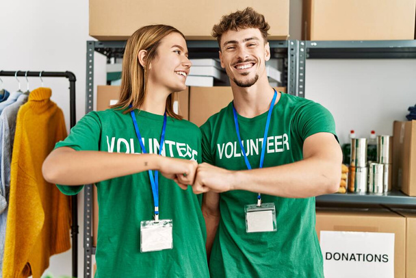 Fiatal spanyol önkéntes pár mosolygó boldog dudor öklök jótékonysági központ. - Fotó, kép