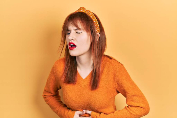 Mujer joven pelirroja que usa suéter naranja casual con la mano en el estómago porque las náuseas, la enfermedad dolorosa sensación de malestar. concepto ache.  - Foto, Imagen