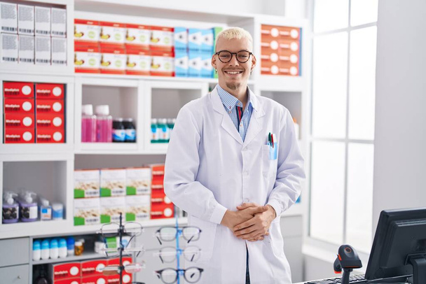 Молодий кавказький чоловік фармацевт посміхається впевнено стоїть в аптеці
 - Фото, зображення