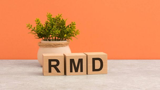 木製のキューブにRMDという言葉があります。 美しいオレンジ色の背景。 ビジネスコンセプト。 コピースペース。 RMD - 必要な最小分配のためのショート - 写真・画像