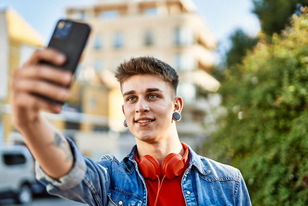Jeune caucasien gars souriant prendre une photo selfie à la ville - Photo, image