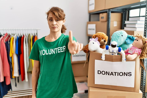 Beautiful caucasian woman wearing volunteer t shirt at donations stand pointing with finger up and angry expression, showing no gesture  - Foto, Imagem