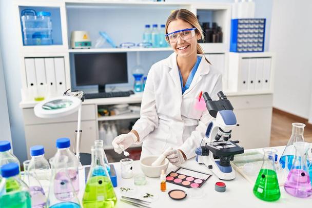 Jonge Spaanse vrouw wetenschapper make-up werken in het laboratorium - Foto, afbeelding