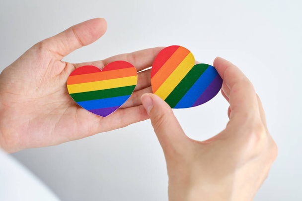 Rainbow heart from paper in woman hands in white t-shirt. LGBT flag. LGBTQIA Pride Month in June. Lesbian Gay Bisexual Transgender. Gender equality. Human rights and tolerance. Rainbow flag - Φωτογραφία, εικόνα