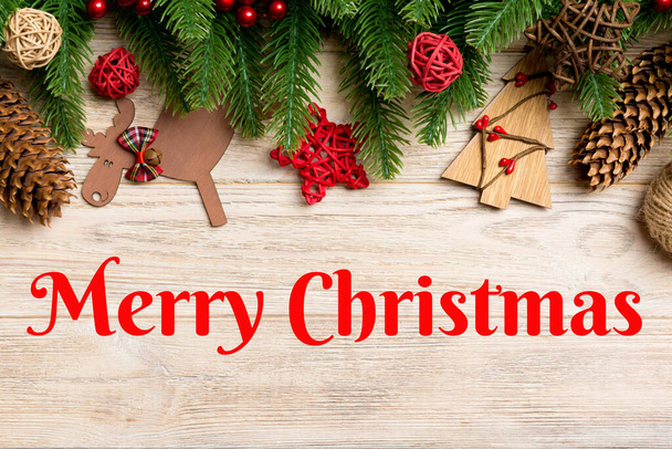Merry Christmas text. Top view of Christmas toys, decorations and fir tree branches on wooden background. New Year holiday concept with copy space. - Photo, Image