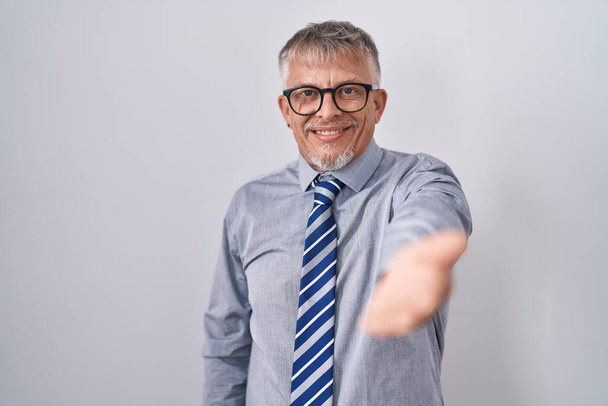 Spanyol üzletember ősz hajjal szemüveges mosolygós vidám kínál tenyérrel segítő és elfogadó.  - Fotó, kép