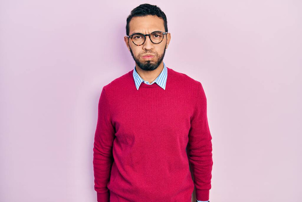 Hispanic man with beard wearing business shirt and glasses puffing cheeks with funny face. mouth inflated with air, crazy expression.  - Zdjęcie, obraz
