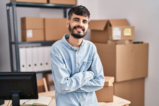 Young hispanic man ecommerce business worker standing with arms crossed gesture at office - Фото, зображення