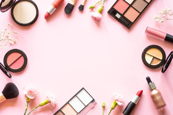 Makeup professional cosmetics on pink background with flowers. Flat lay with copy space. - Foto, Imagem