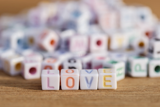 Love written in letter beads on wood background - Foto, imagen