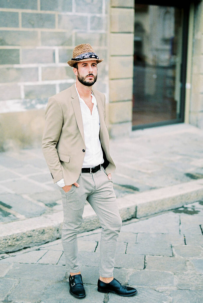 Man in a hat stands on the paving stones near the stone building. High quality photo - Foto, immagini