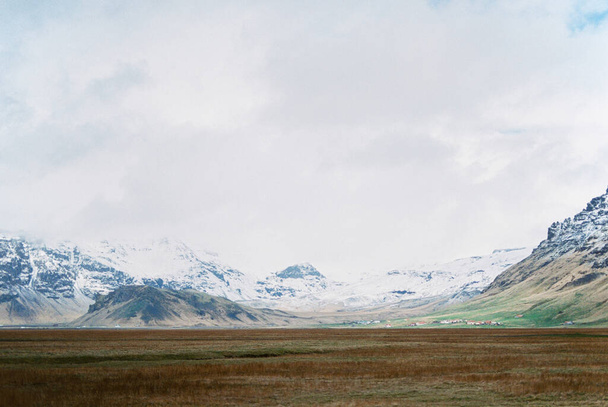 Laaksossa kuiva ruoho taustaa vasten lumipeitteisiä vuoria. Islanti. Laadukas kuva - Valokuva, kuva