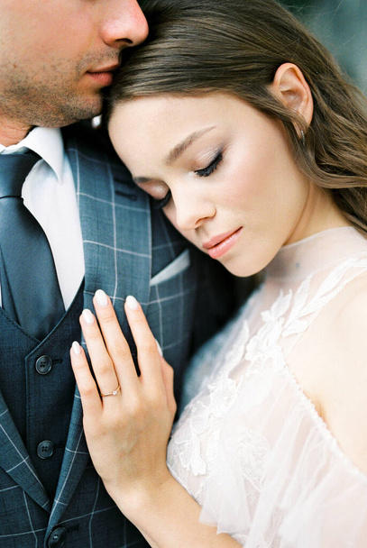 Bride laid her head on the groom shoulder, touching his chest with her hand. High quality photo - Foto, Imagen
