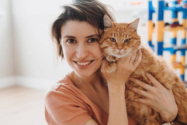 Portrait of caucasian woman smiling and hug her cat while taking rest at home. Love pet concept. Lifestyle, female beauty concept.  - Fotó, kép