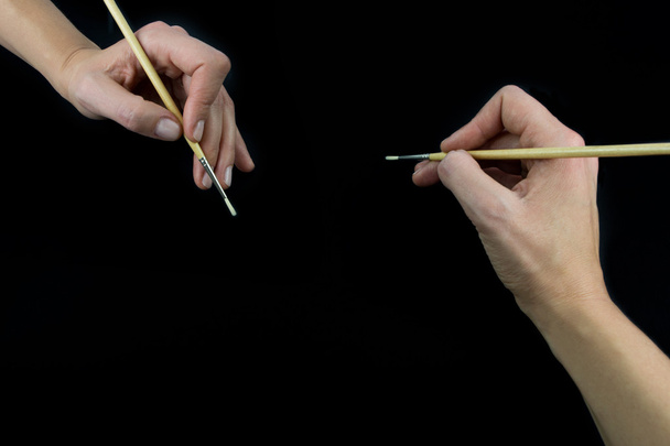 Рука тримає пензлик, встановлений ізольовано на чорному тлі
 - Фото, зображення