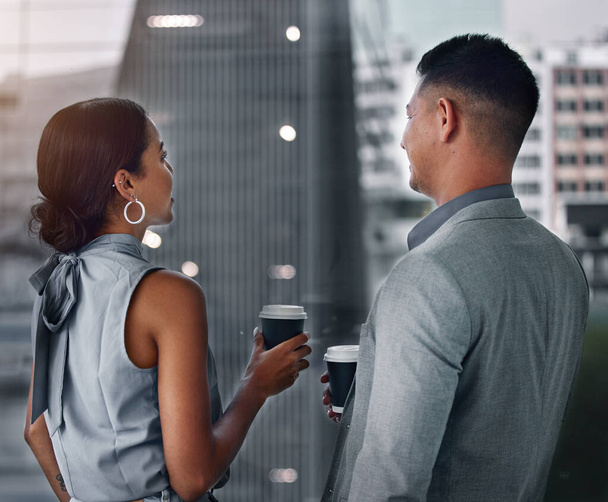 Coworkers and coffee get your through late shifts. two businesspeople standing together in the office and having a discussion in the evening - 写真・画像