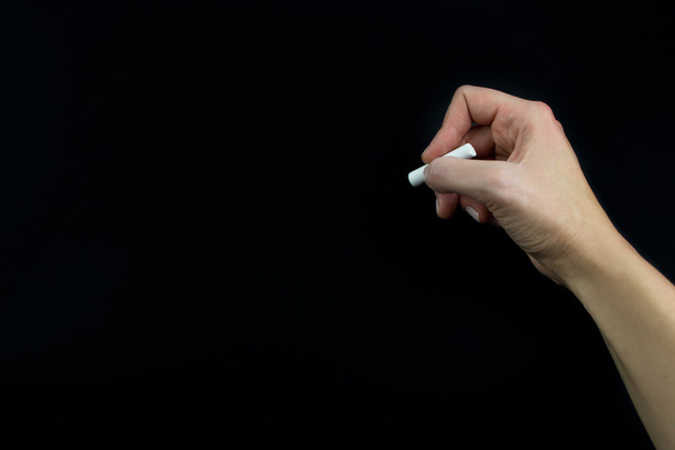 Hand holding chalk isolated on black background - Foto, Imagem