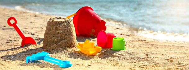 Set of plastic beach toys on sand near sea. Banner design - Φωτογραφία, εικόνα