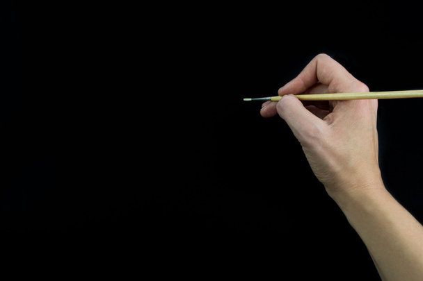 Рука тримає пензлик, ізольований на чорному тлі
 - Фото, зображення