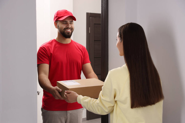 Woman receiving parcel from courier at home - Photo, image