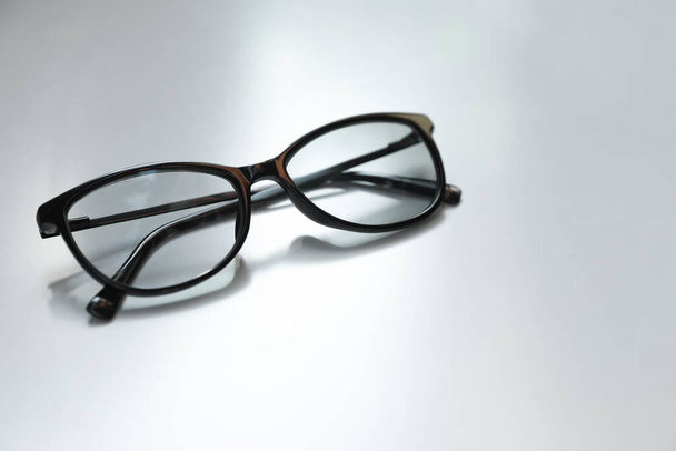 Stylish black eye glasses on white table. Space for text - Foto, Imagen