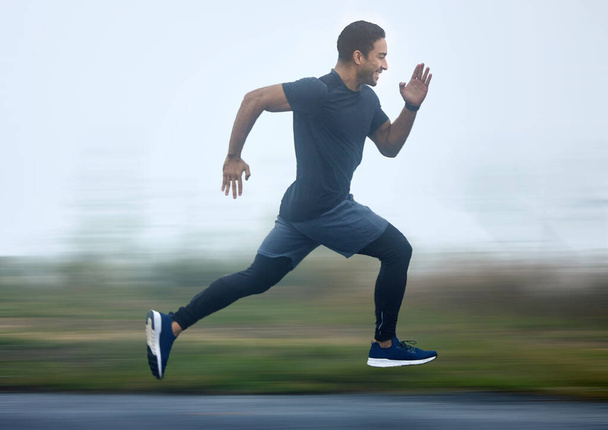 Boosting with speed in every step. a sporty young man running outdoors - Foto, Imagen