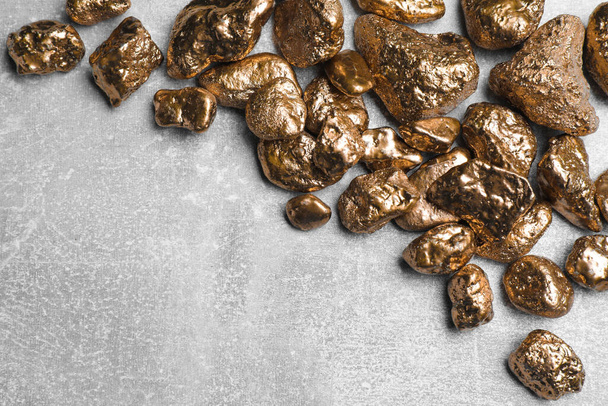 Pile of gold nuggets on light grey table, flat lay. Space for text - Fotografie, Obrázek