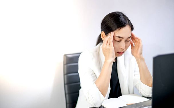 Junge Asiaten fühlen sich von der Arbeit gestresst, während sie zu Hause vor einem Laptop sitzen. Konzept verärgert gestresste Mitarbeiter oder Studenten, die der Arbeit überdrüssig sind, besorgt über das Online-Problem. - Foto, Bild