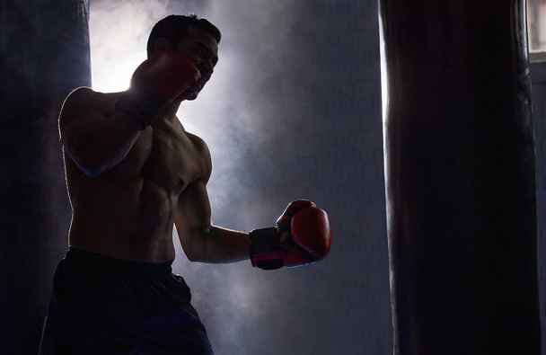 Its all about the combinations. a silhouetted young male boxer working out on a punching bag in the gym - 写真・画像