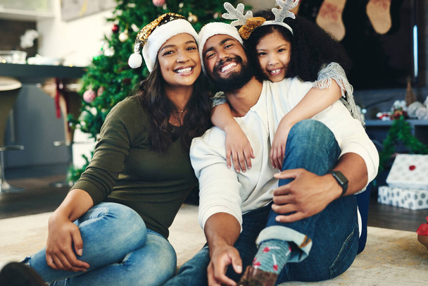 The spirit of Christmas summed up in one moment. Portrait of a happy young family celebrating Christmas at home - Photo, Image
