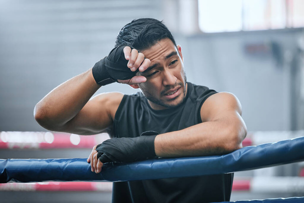 Fit, active or healthy boxing man feeling tired, hot and wiping sweat after workout, training or exercise in ring. Sporty, athletic or strong boxer upset after losing kickboxing fight or sports match. - Foto, Bild