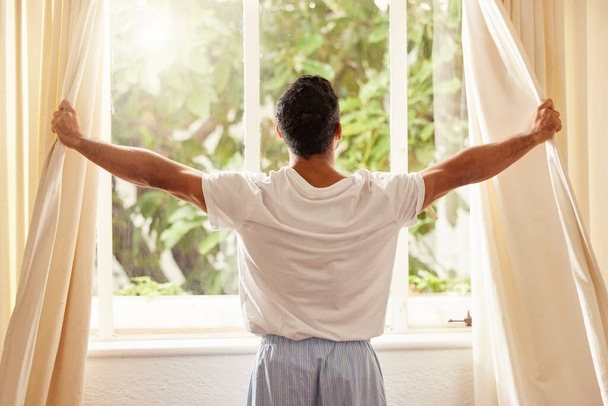 I woke up feeling grateful. a man opening the curtains at home on a sunny day - Foto, Bild