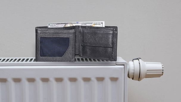 dollar banknotes on central heating radiator, the concept of expensive heating costs, front view - Zdjęcie, obraz