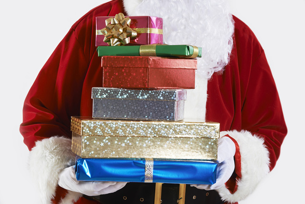 Gros plan du Père Noël tenant une pile de cadeaux emballés cadeaux
 - Photo, image