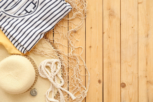Clothes with hat, compass, rope and fish net on wooden background - Foto, Imagem