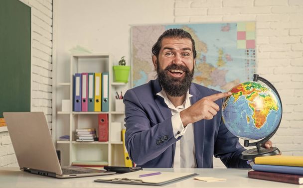 Male teacher in the classroom teaching geography pointing to a world map, education. - Фото, зображення