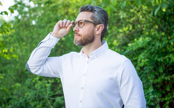 Professional man looking into distance in eyeglasses natural background, eyesight. - Fotoğraf, Görsel