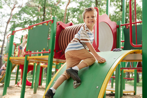 Усміхнений хлопчик грає на дитячому майданчику в літній день
  - Фото, зображення