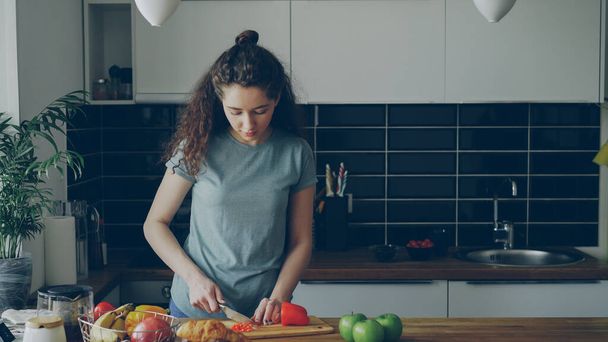Curly beautiful caucasian woman in headphones dancing prepearing breakfast in kitchen at home - Fotografie, Obrázek