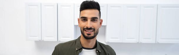 Positive muslim man looking at camera at home, banner  - 写真・画像